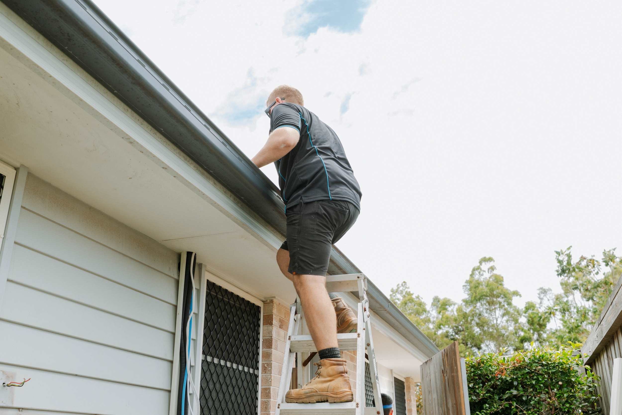 Technician climbing ladder to roof during ducted aircon installation in Kallangur