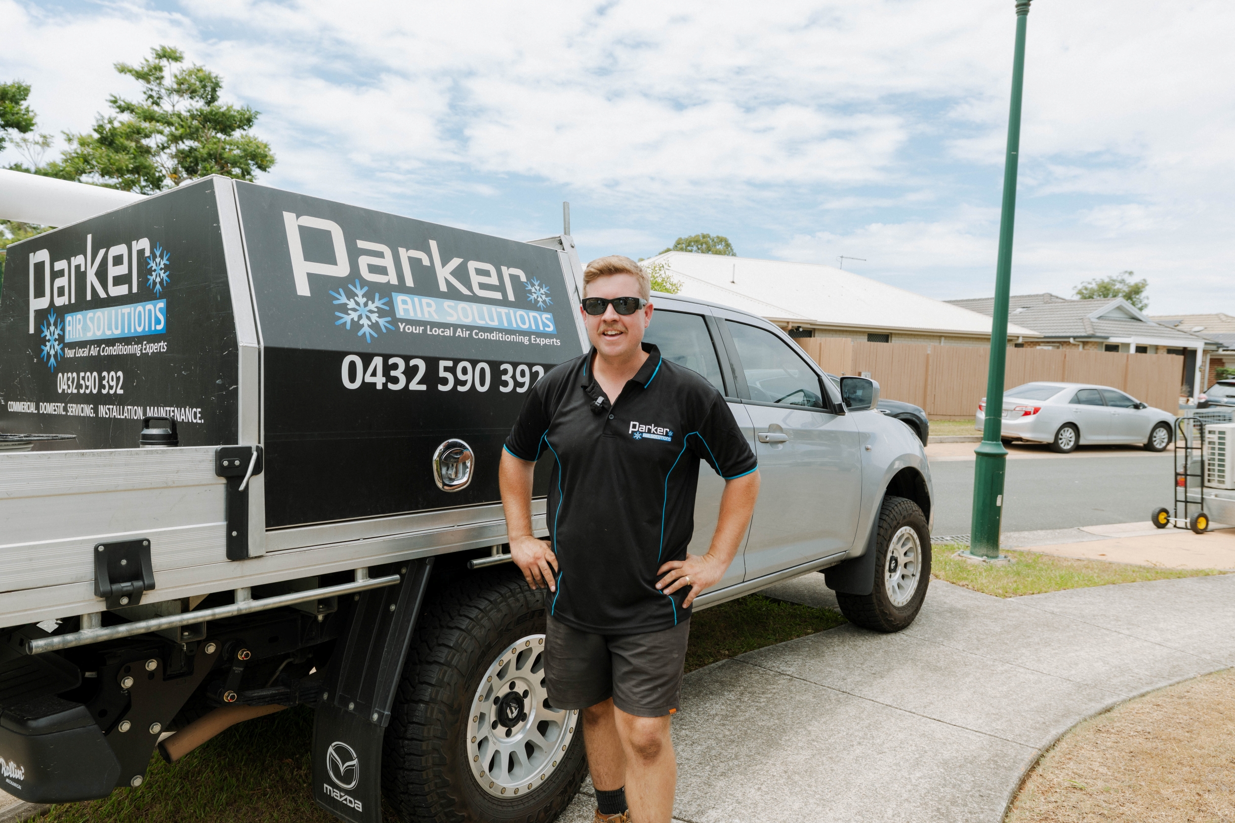 Parker Air Solutions technician standing with branded service vehicle in Kallangur