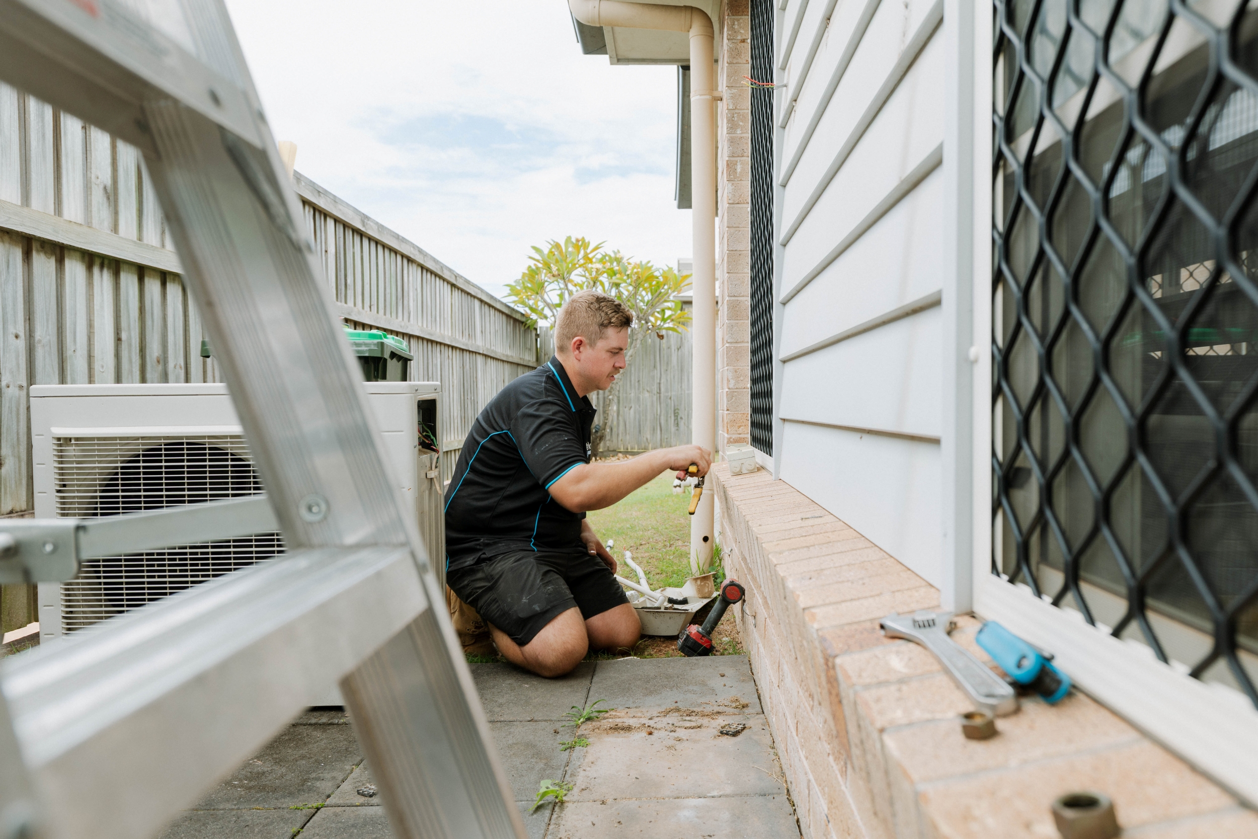 Technician connecting outdoor unit pipework for ducted air conditioning in Kallangur