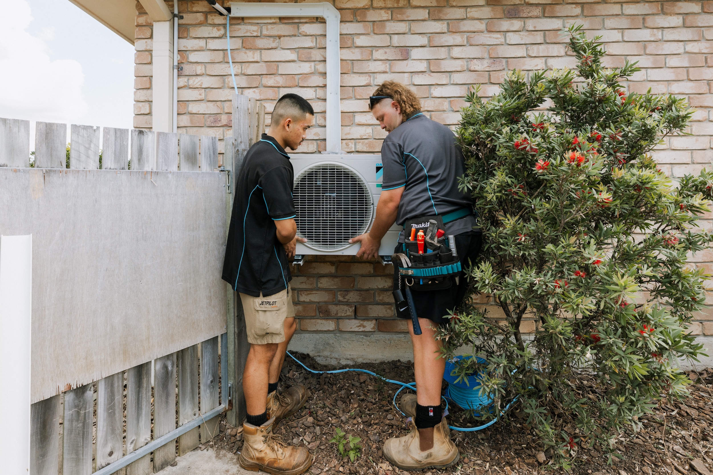 Two-person team safely lifting AC compressor